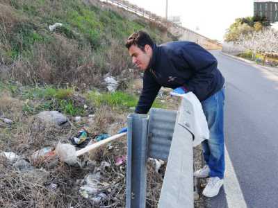 Estrae anche un bastone, con il quale si aiuta a raccogliere gli oggetti pi� lontani gettati oltre il guardrail